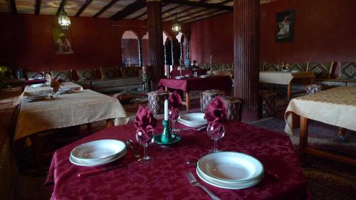 a table with plates and glasses on a red table cloth at Maison berbère in Ouarzazate