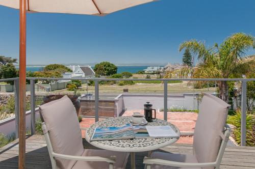 a table and chairs on a balcony with a view of the ocean at Whale Away Guest House in Hermanus