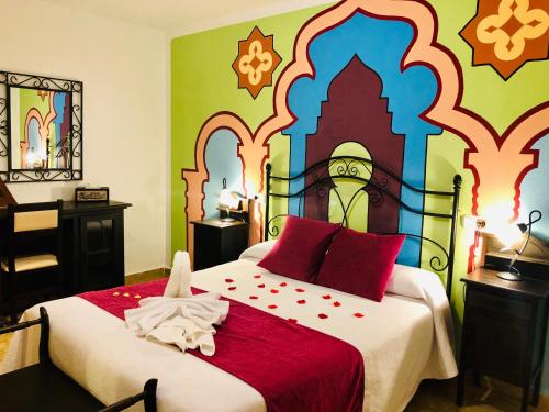 a bedroom with a large bed with a colorful wall at Hotel Puerta Nazarí in Órgiva