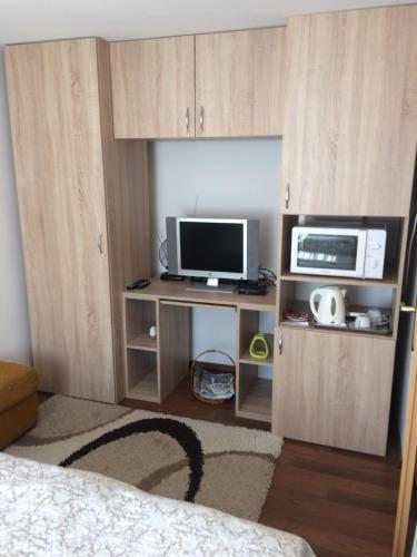 ヴィシェグラードにあるLiliom Vendégházのテレビ、デスク、電子レンジが備わる客室です。