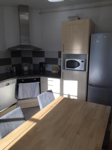 une cuisine avec une table en bois et un réfrigérateur dans l'établissement Mansard de Vallet campagnard, à Bléré