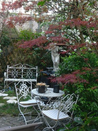 two chairs and a table in a garden with flowers at Lamaison du phare honfleur chambres d'hotes et jacuzzi privé in Honfleur