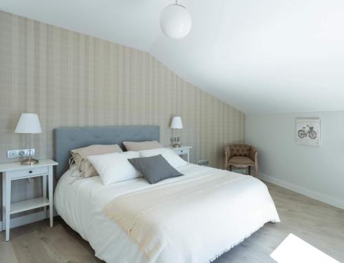 1 dormitorio con 1 cama grande con sábanas y almohadas blancas en Indigo Rooftop, en A Coruña