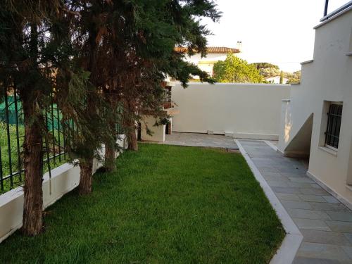 a yard with trees and a white fence at COZZY STUDIO IN NEA MAKRI in Nea Makri