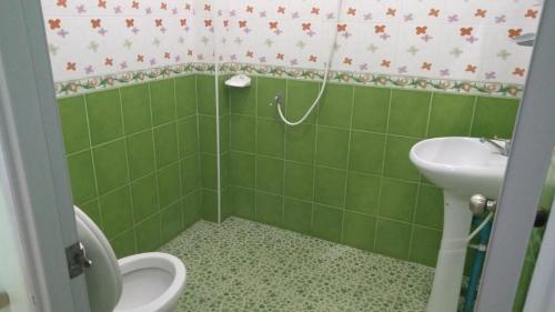 a green bathroom with a toilet and a sink at บ้านพักน้องจ็อบ in Baanphakrimlay 
