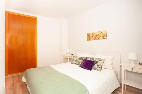 Schlafzimmer mit einem weißen Bett und einem Holzschrank in der Unterkunft Sitges Center & Beach Espalter in Sitges