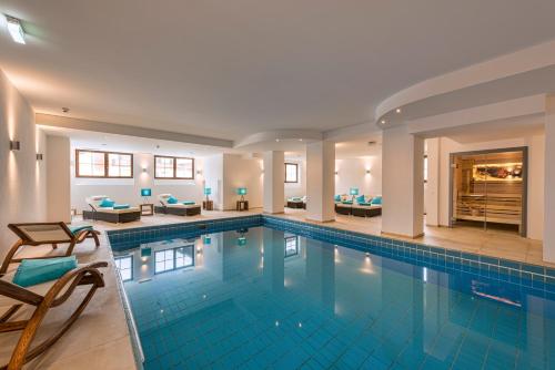 a swimming pool in a hotel with chairs at Ruhpoldinger Hof in Ruhpolding