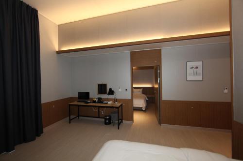 a hotel room with a bed and a desk with a computer at Tongyeong Bridge Hotel in Tongyeong