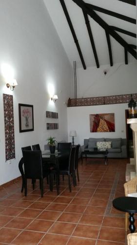 a living room with a table and chairs and a couch at Country house Cortijo de la fuente in La Bobadilla