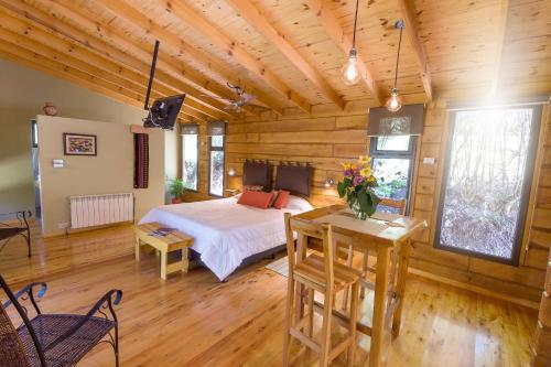 1 dormitorio con 1 cama, mesa y sillas en Akapana Suites en Villa Berna