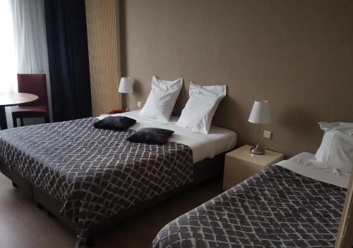 two beds in a hotel room with towels on them at Hôtel La Côte d'Or in Philippeville