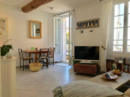a living room with a television and a table with chairs at Pimms Apartment in Antibes