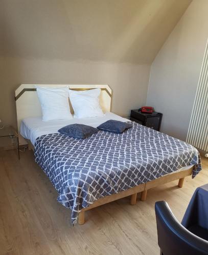 a bedroom with a bed with a blue and white comforter at Hôtel La Côte d'Or in Philippeville