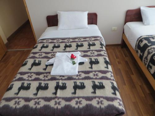 a hotel room with two beds with a flower on the bed at La Casa De Yoni in Puno