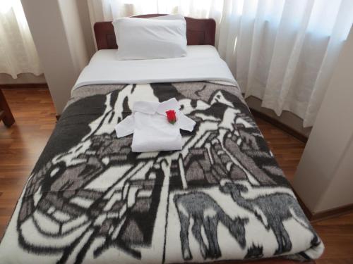 a bed with a black and white blanket on it at La Casa De Yoni in Puno