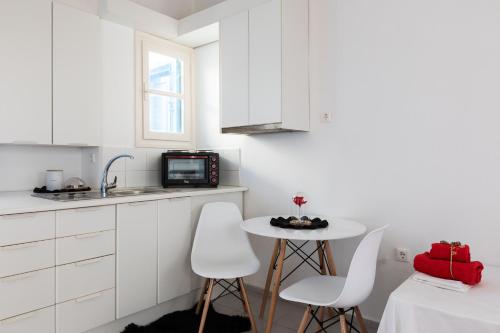 a kitchen with white cabinets and a small table and chairs at Izabela's House Mykonos Town in Megali Ammos