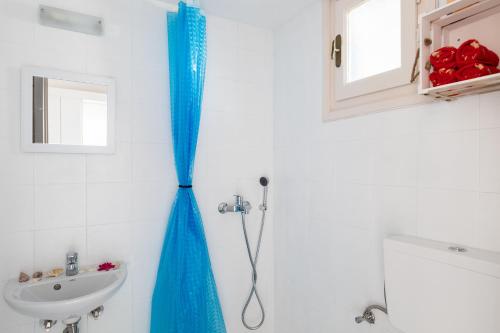 a blue shower curtain in a bathroom with a sink at Izabela's House Mykonos Town in Megali Ammos