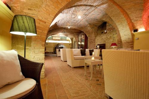 a living room with white furniture and a brick wall at Hotel Villa Beccaris in Monforte dʼAlba