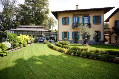 une grande maison avec une pelouse verte en face de celle-ci dans l'établissement Hotel Villa Beccaris, à Monforte dʼAlba