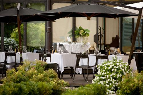 un restaurante con mesas y sillas blancas y sombrilla en Hotel Villa Beccaris, en Monforte dʼAlba