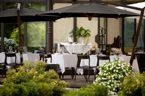モンフォルテ・ダルバにあるホテル ビラ ベカリスの白いテーブルと椅子、傘が備わるレストラン