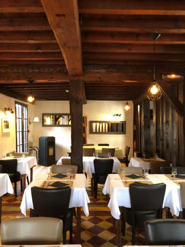 a restaurant with white tables and chairs and wooden ceilings at Clos 85 in Linxe