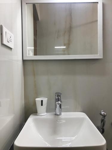 a bathroom sink with a cup and a mirror at Serenity Manor in Coonoor