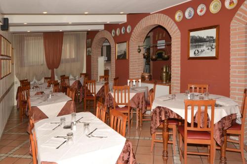 een restaurant met witte tafels en stoelen en rode muren bij Albergo Cavallucci in Sermide