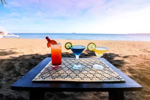 a picnic table with two drinks on the beach at Ceazar's Place in Dauin