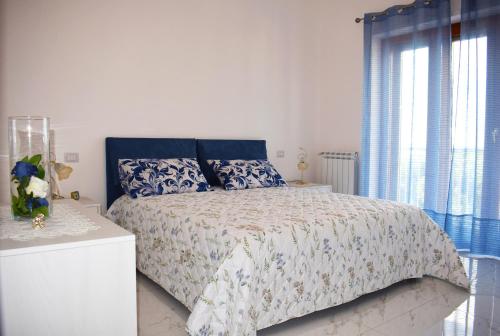 Schlafzimmer mit einem Bett mit einer blauen und weißen Bettdecke in der Unterkunft La Perla Bianca in Sorrent