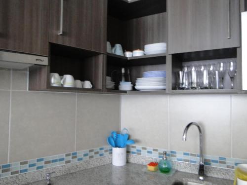 una cocina con fregadero y armarios con vajilla en Condominio Arena Maris, en Algarrobo