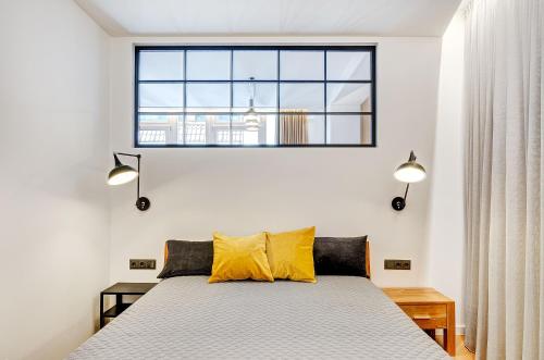 um quarto com uma cama com almofadas amarelas e uma janela em Downtown apartment in Vilnius str. em Vilnius