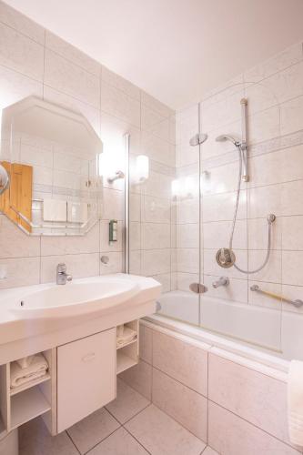 a white bathroom with a sink and a shower at Hotel Serles in Mieders