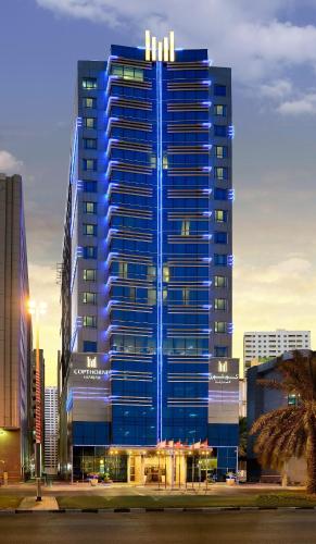 a tall building with blue lights on it at Copthorne Hotel Sharjah in Sharjah