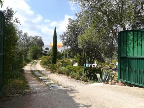a dirt road with a green gate on the side at Alagoas Park in Loulé