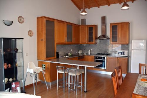 a kitchen with wooden cabinets and a island with bar stools at Casa do Outeiro in Penacova