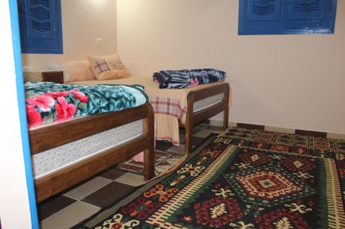 two beds in a room with a rug at Tunis Village Chalet in Fayoum Center