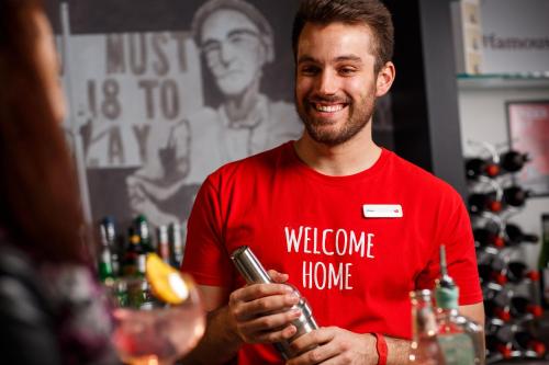 a man standing in a bar holding a drink at ibis Brighton City Centre - Station in Brighton & Hove