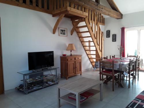 Il comprend un salon doté d'une télévision et d'une table avec des chaises. dans l'établissement Aux delices de Saleix, à Sorges