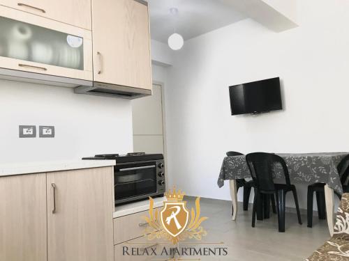 a kitchen with a stove and a table with chairs at Durmishi Rooms & Apartments & Beach in Sarandë