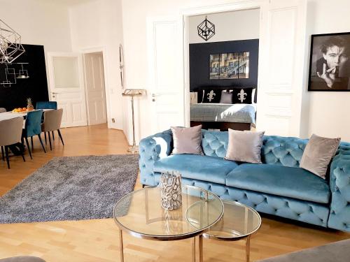 ein Wohnzimmer mit einem blauen Sofa und einem Glastisch in der Unterkunft Belle Epoque in Wien