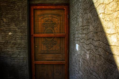a wooden door in a wall with a shadow at Tunis Village Chalet in Fayoum Center