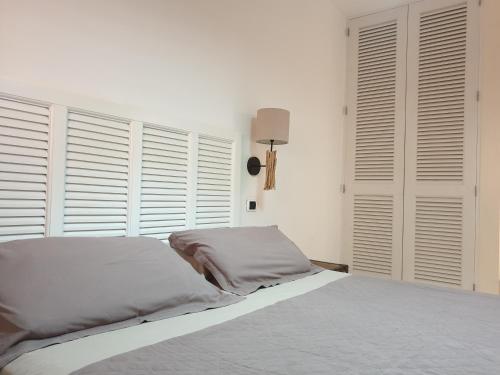 a bedroom with a bed with white walls and windows at Aparthotel Por do Sol in Sal Rei