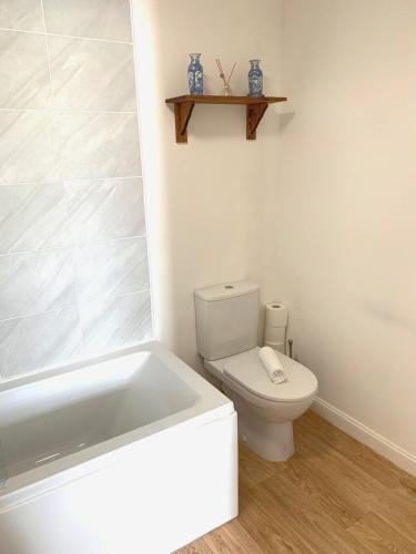 a bathroom with a white toilet and a bath tub at Home Crowd Luxury Apartments in Doncaster