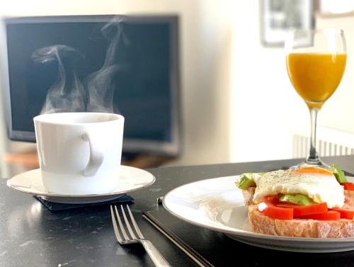 a sandwich on a plate next to a cup of coffee at Home Crowd Luxury Apartments in Doncaster