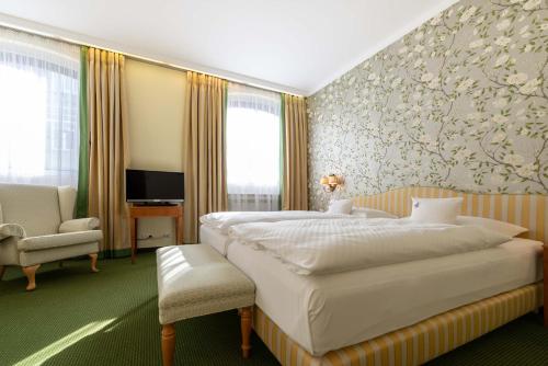 a hotel room with a large bed and a chair at Romantik Hotel zur Post in Fürstenfeldbruck