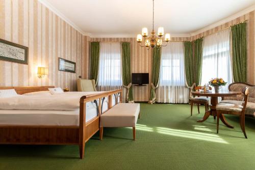 ein Hotelzimmer mit einem Bett, einem Tisch und Stühlen in der Unterkunft Romantik Hotel zur Post in Fürstenfeldbruck