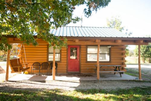 a log cabin with a red door and a bench at River Bluff Cabins in Rio Frio
