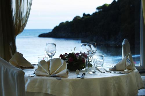 a table with wine glasses and flowers on a beach at Grand Hotel Il Ninfeo in Gaeta