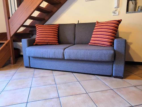 a blue couch with two pillows on a tile floor at Appartamento la Torre Vinadio in Vinadio